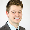 Man with short brown hair in black business suit