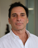 headshot of white man with dark hair open collar white shirt
