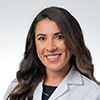 Headshot of woman in white lab coat with dark brown long hair