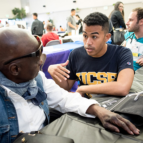 Medical students do blood pressure checks and and dental students do screenings with community members at the Southeast Community Health Fair. Med student Dereck Paul talks to participant Mary Crenshaw before her blood pressure screening.