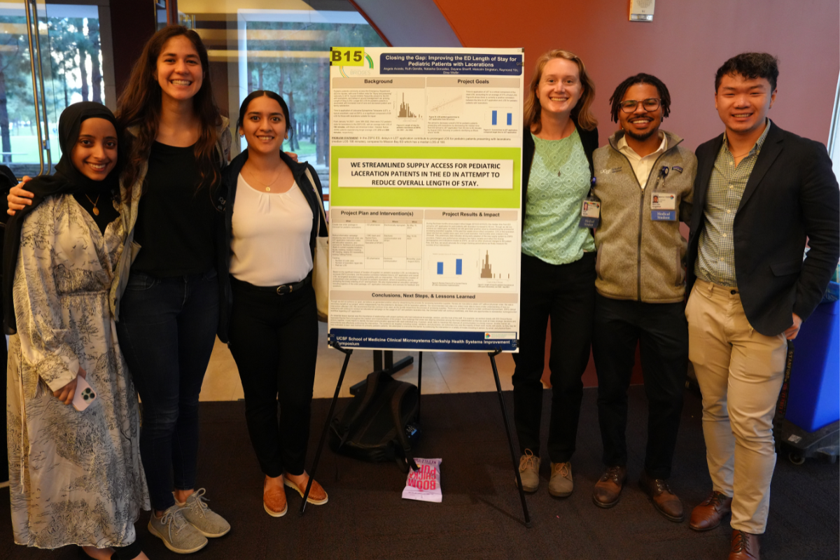 Three students stand on either side of a poster in a conference room.