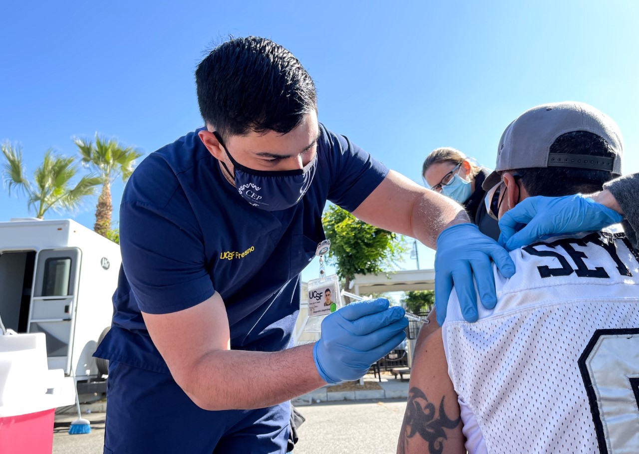 Student administering COVID-19 vaccine at a community clinic.