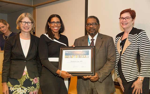 four faculty posing with award certificate